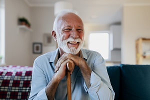 older man smiling at camera holding cane